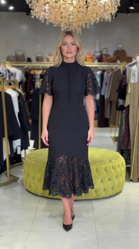 Full front view of model wearing black mock neck lace midi dress with trumpet hem