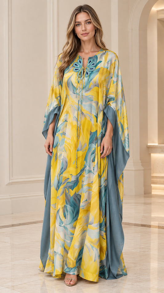 Front view of woman wearing yellow and teal floral caftan maxi dress with butterfly neckline appliqué