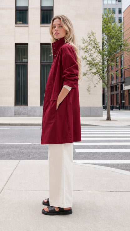 Side profile of woman wearing burgundy mid-length light coat