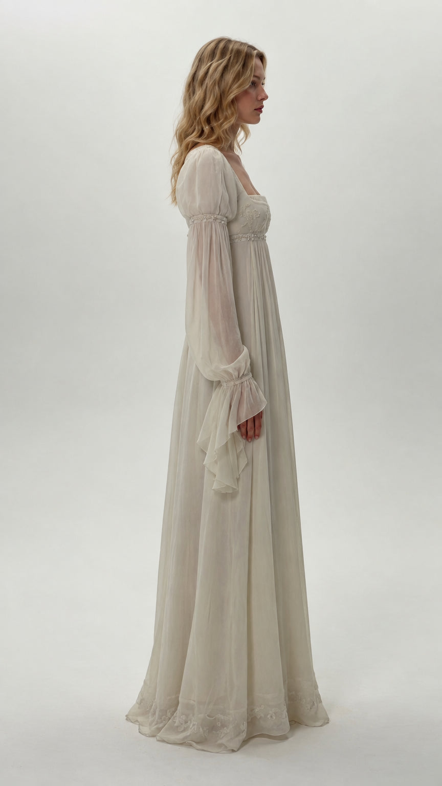 Side profile of model wearing ivory long bell sleeve empire waist dress