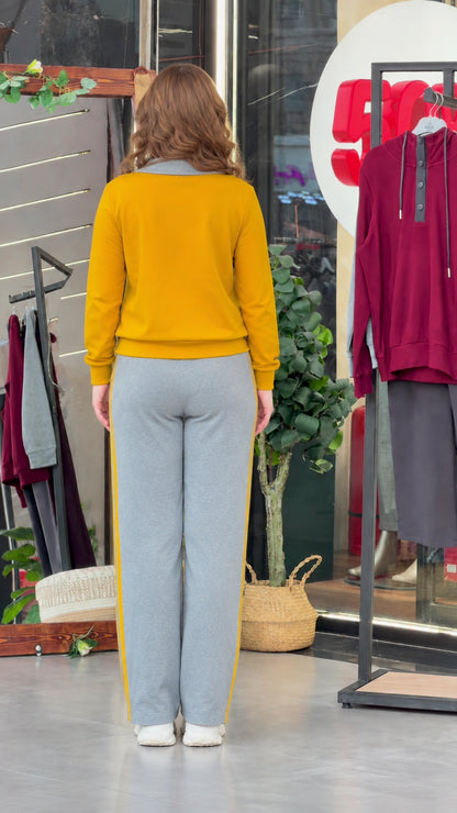 Back view of model wearing mustard yellow pullover top and grey straight-leg sweatpants
