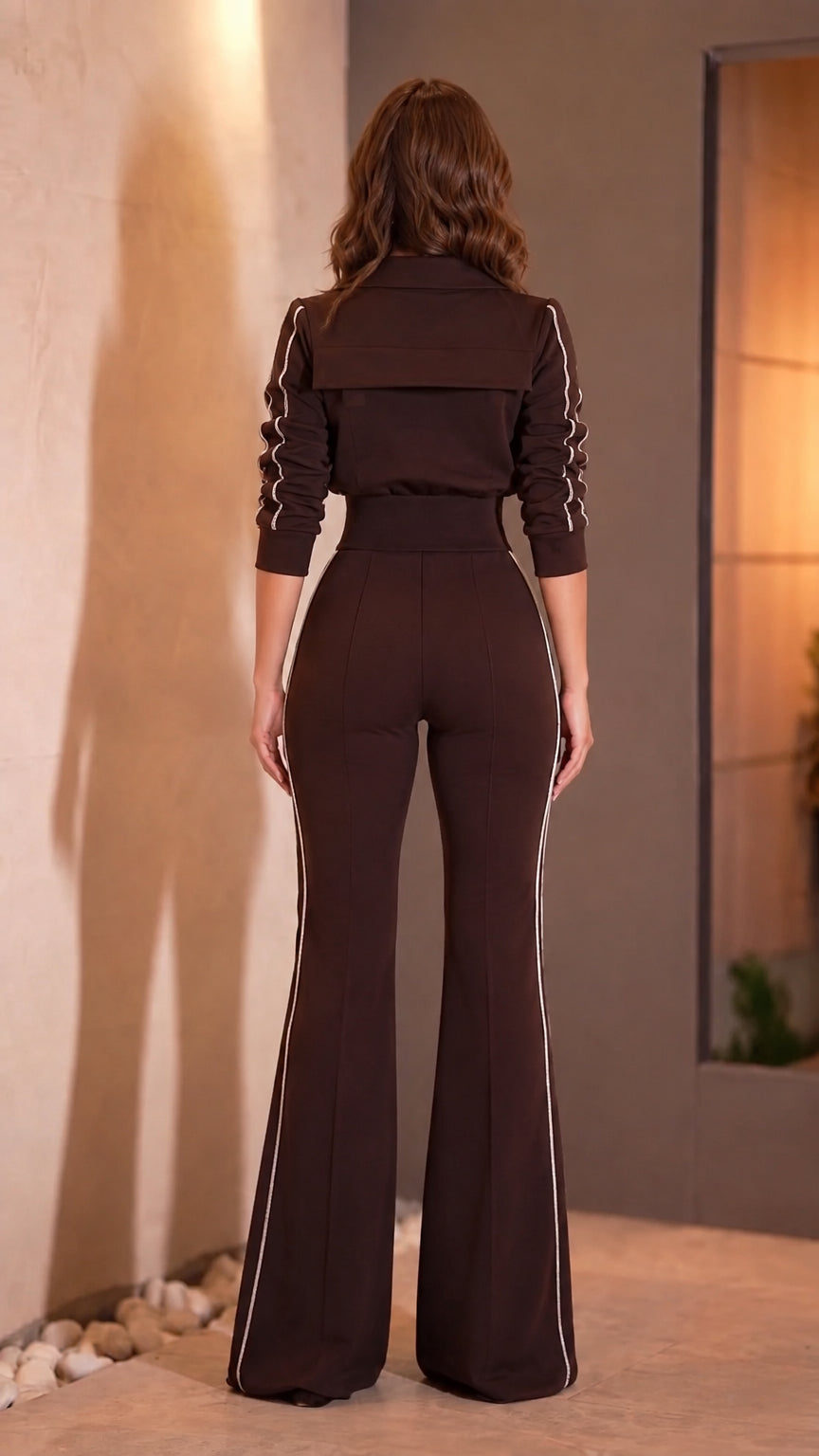 Back view of woman wearing chocolate brown long sleeve flare jumpsuit