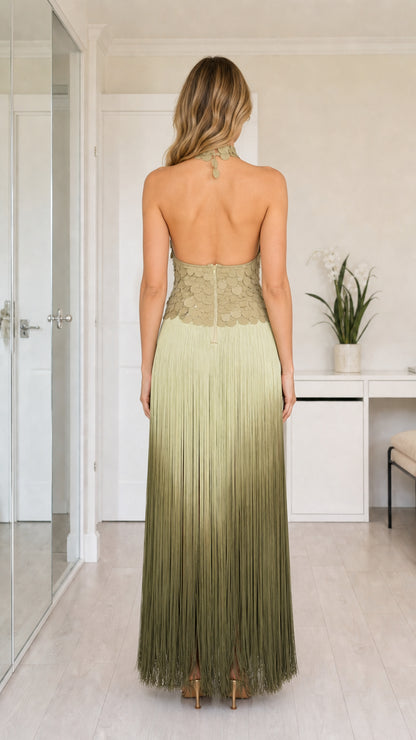 Back view of sage green halter dress featuring open back and fringe skirt