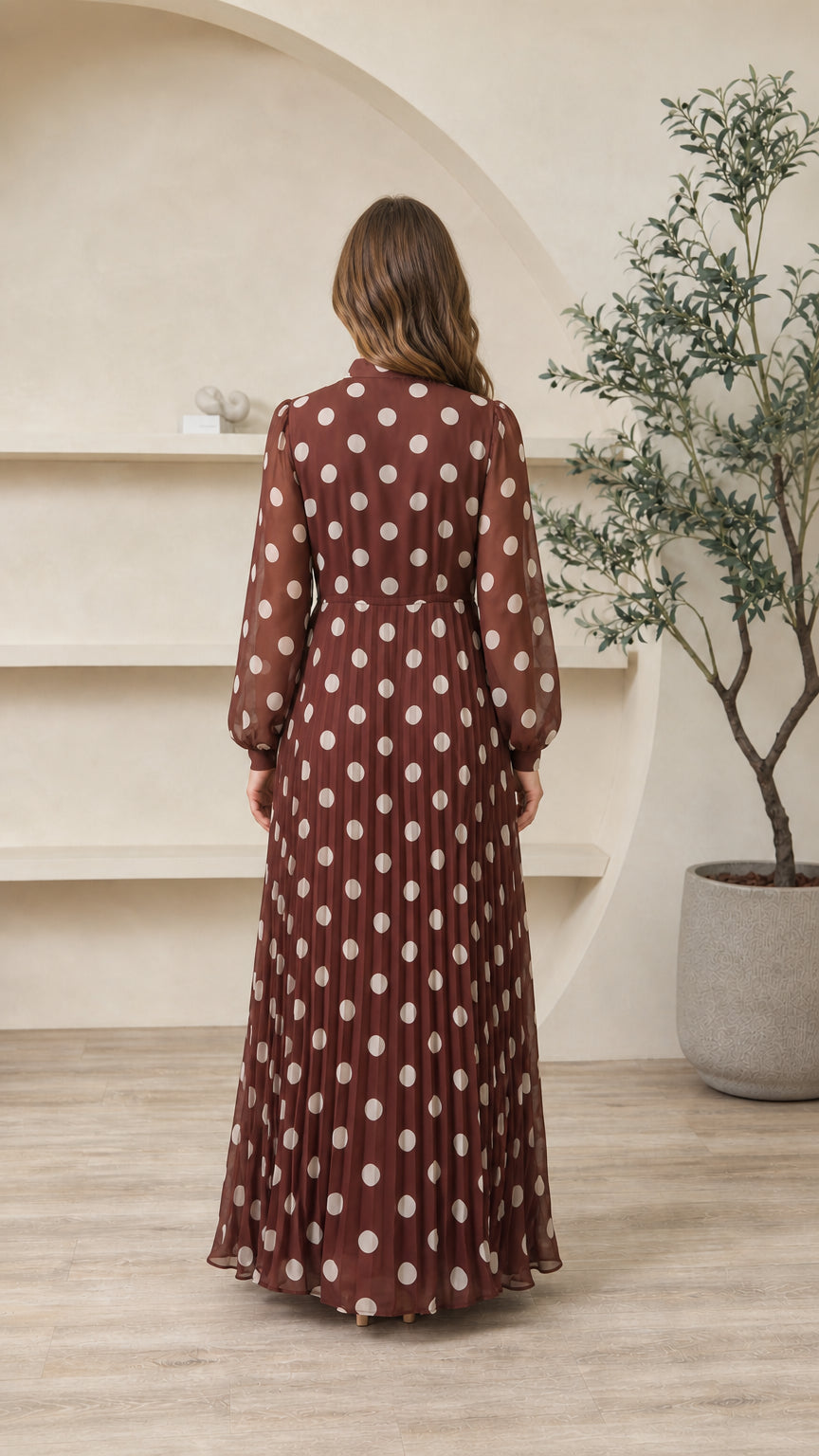 Back view of chocolate brown polka dot maxi dress showing pleated skirt silhouette