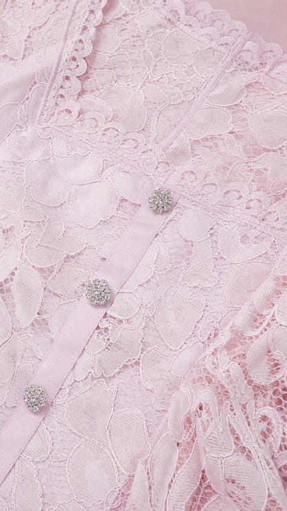 Close-up detail of the blush pink floral lace fabric, scalloped neckline, and crystal buttons