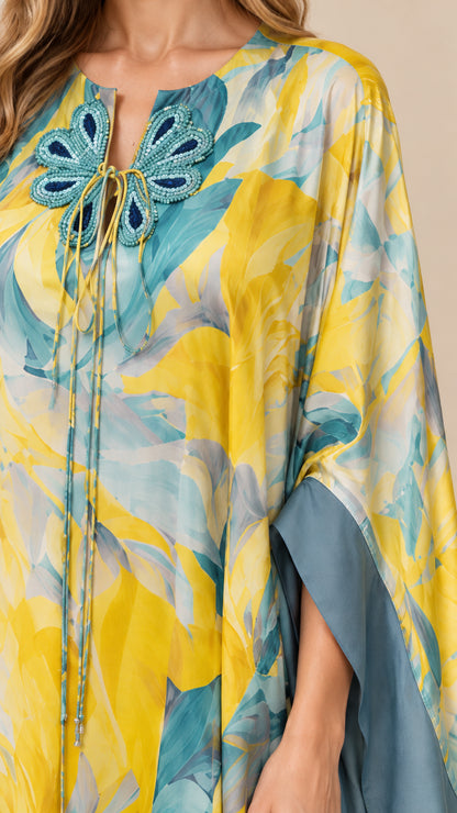 Close-up of intricate butterfly appliqué neckline with tie detail on yellow floral caftan