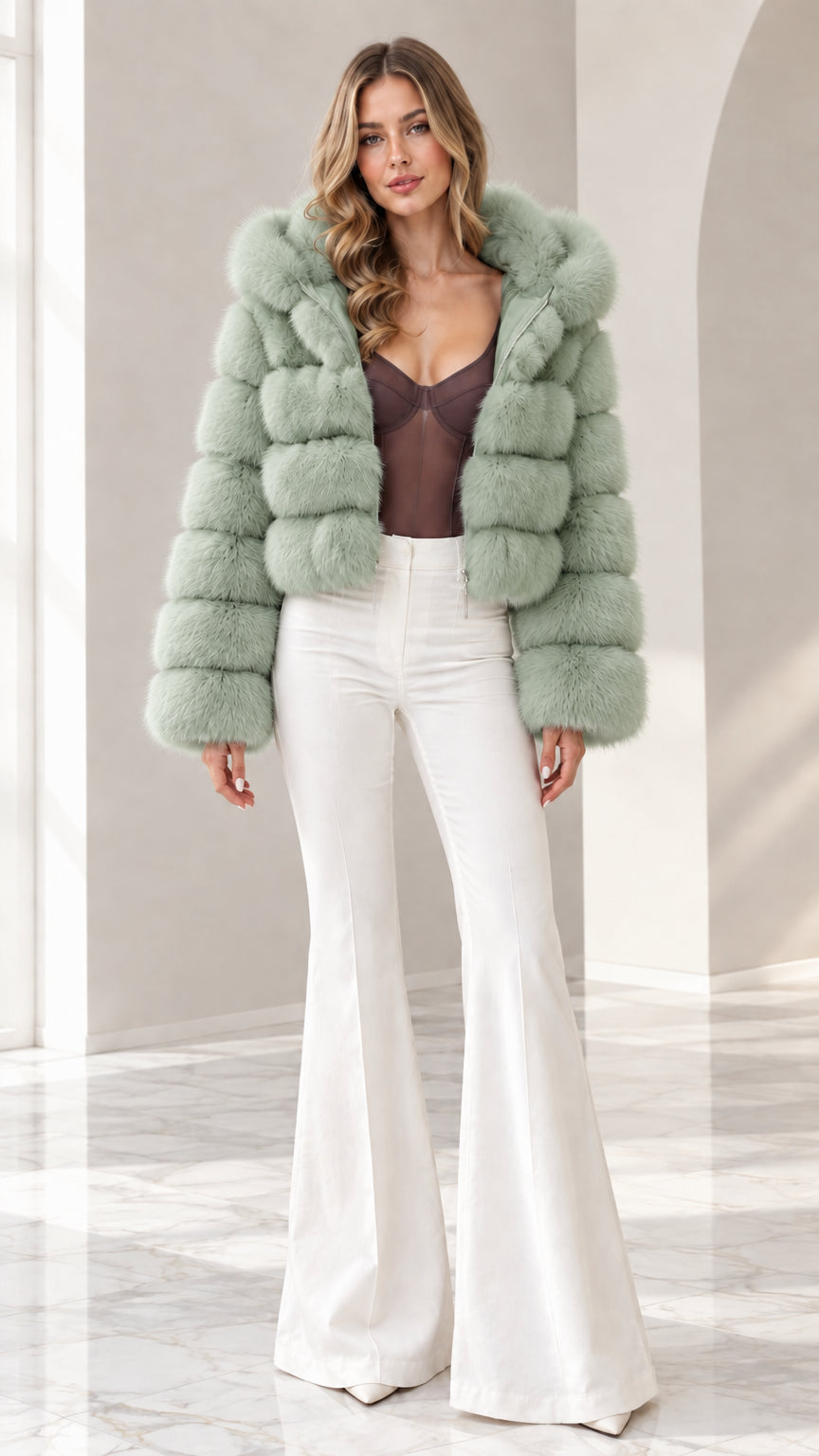 Model wearing sage green cropped hooded faux fur jacket with white pants