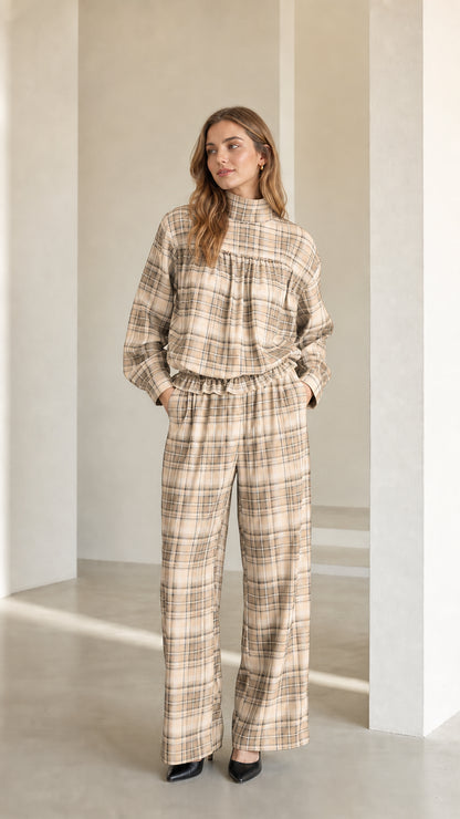 Model wearing warm beige plaid mock neck blouse and matching trousers set